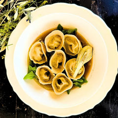 Porco Preto tortellini in its own broth, with spinach and grilled spring onion